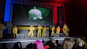 Bailarines y bailarinas con el icónico mono amarillo y máscara de gas de Breaking Bad. / Kami